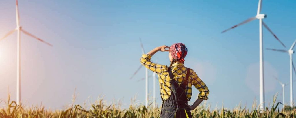 Boerin kijkt uit over een veld vol graan met windmolenpark