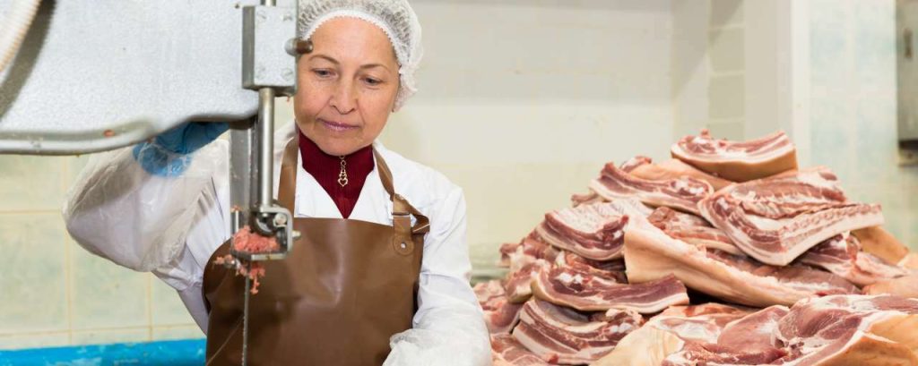 Vrouw snijdt vlees in een fabriek adobe stock change inc