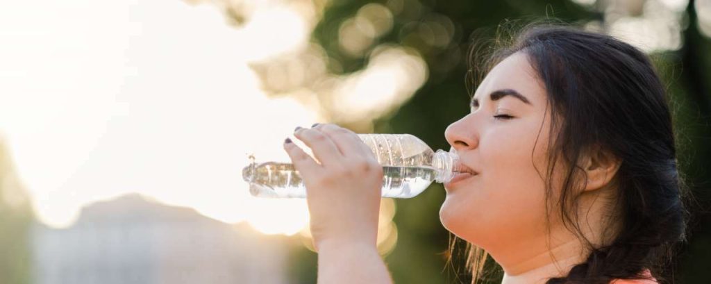 Vrouw water plastic fles zon roze shirt change inc adobe stock