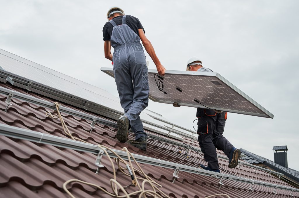 Adobe Stock mannen op dak aan het werk met zonnepanelen