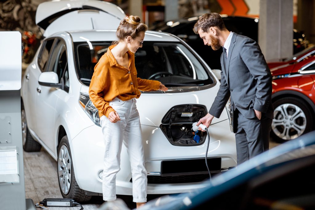 Auto opladen verkoper man vrouw oranje blouse