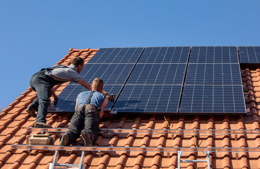 Adobe Stock mannen plaatsen zonnepanelen op dak