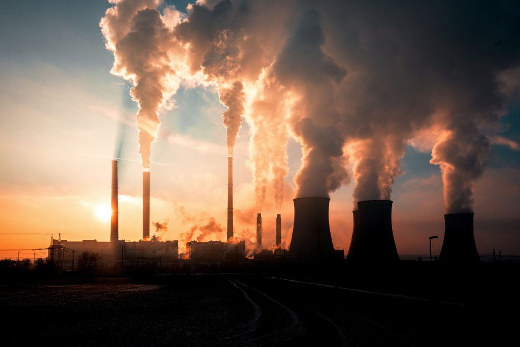 Adobe Stock rokende fabriek met zonsondergang op de achtergrond